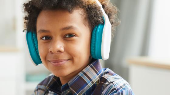 photo of a young boy wearing headphones smiling at the camera